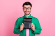 Photo of funky pretty man dressed green shirt eyewear smiling holding calculator isolated pink color background