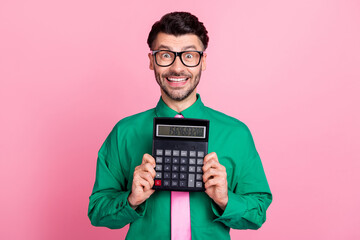 Wall Mural - Photo of funky pretty man dressed green shirt eyewear smiling holding calculator isolated pink color background