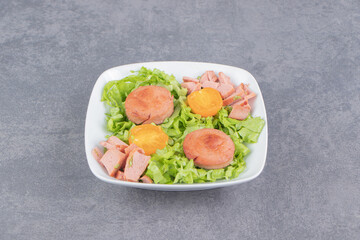 Delectable lettuce leaves and sausage, on the plate , on the marble background