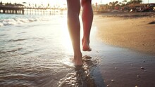 View Of Back Close Up Legs Of Young Beautiful Woman. Walking Barefoot On Sand On Beach By Sea. Summer Lifestyle. Travel And Tourism In Summer. Natural Landscape By Water. Outdoors Daytime Landscape.