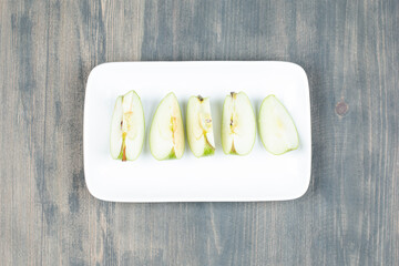 Wall Mural - Green apple sliced isolated on a white plate