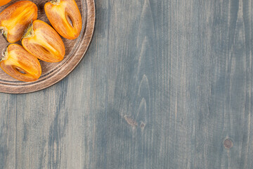 Wall Mural - Sliced delicious persimmon in a wooden plate