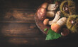 Autumn forest background or internet banner with wild  mushrooms porcini or Boletus Edulis and harvested chestnuts on dark wooden background, top view, copy space. Autumn harvest concept