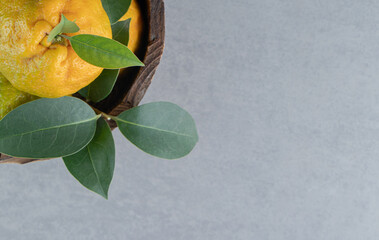 Wall Mural - Tasty tangerines piled in a wooden bucket on marble background