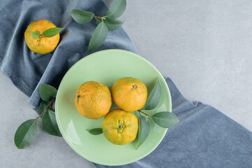 Wall Mural - Tangerines and leaves on a platter on marble background