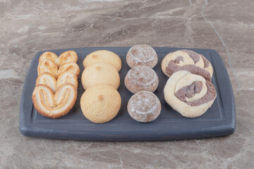 A bundle of various cookies on a board on marble background