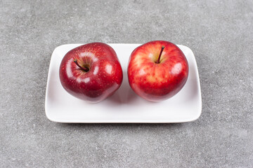 Two red apples on white plate