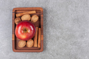 Wall Mural - Red apples, walnuts and cinnamon sticks on wooden plate