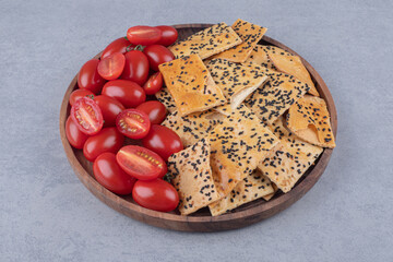 Wall Mural - Sesame coated bread and tomato slices piled on a wooden tray on marble background