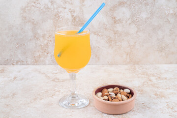 Wall Mural - A small bowl of almonds and pistachios and a glass of juice on marble background