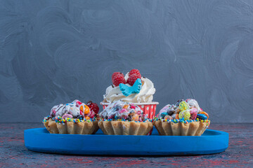 Wall Mural - Cupcakes on a blue platter on abstract background