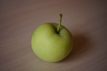 One ripe green apple on wooden table.