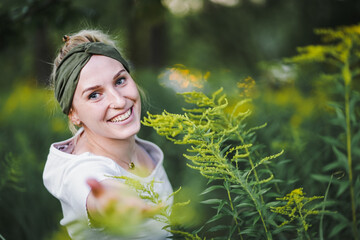 Wall Mural - happy tattooed alternative & spiritual looking hipster woman smiling into the cam outside in a park with a green refreshed nature forest background
