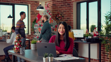Wall Mural - portrait of employee sitting at desk to work on laptop, sending email before celebrating winter holi
