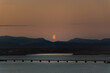 Orange perfect Half Moonrise over Borgarnes, the bridge and the fjord, in West Iceland