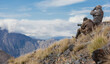 Hunters in camouflage use binoculars and telescope to search for animals in the mountains.