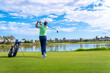 © unai - Man playing golf at golf club by a lake, hitting the ball