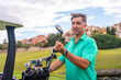 © unai - Man playing golf at golf club, checking golf clubs in buggy before starting to play