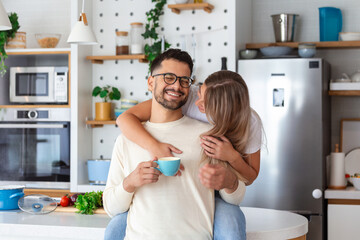 romantic couple in love spending time together in kitchen. cute young couple drinking coffee in kitc