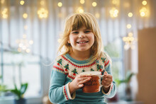 Little Preschool Girl Holding Cup With Hot Chocolate With Marhsmallows. Happy Child Drinking Sweet Cocoa By Window With Christmas Lights In Winter. Cozy Family Celebration Of Xmas.