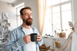 © fotofabrika - Young bearded man smiling and drinking coffee at home