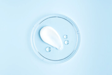 Poster - smear of cream stroke and round transparent drops of gel serum in a petri dish on a blue background. Concept laboratory tests and research, making and testing cosmetic