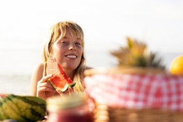 Wall Mural - Cheerful young woman enjoy at tropical sand beach. Portrait of happy girl with fruit. Young woman having a picnic on the beach