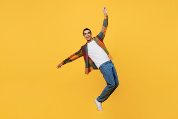 Full body young middle eastern man 20s he wear casual shirt white t-shirt look camera with outstretched hands dance stand on toes isolated on plain yellow background studio People lifestyle concept.