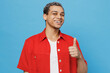 Young smiling happy satisfied cheerful man of African American ethnicity 20s he wearing red shirt show thumb up gesture isolated on plain pastel light blue cyan background. People lifestyle concept.
