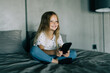 © F8  \ Suport Ukraine - Little girl looking mobile phone on the bed.