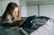 © F8  \ Suport Ukraine - Cute little girl use digital tablet while lying in bed