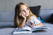 © F8  \ Suport Ukraine - Little girl sitting on the sofa reading a book. Concept of girl with a book.