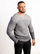 © oleg_ermak - Handsome confident model. Man dressed in gray sweater and black pants with hand in pocket. Fashion male posing near white wall in studio.