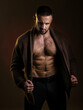 © oleg_ermak - Studio shot of a handsome bare-chested athlete. A man takes off her jacket and shows his muscular body. Fitness, strength, courage, a trained man standing against a dark background.