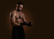 © oleg_ermak - Studio portrait of fighting muscular man puts on fighting gloves posing on dark background. The concept of mixed martial arts. Brutal bodybuilder energy and power boxing.