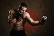 © oleg_ermak - Studio portrait of fighting muscular man in black fighting gloves posing on dark background. The concept of mixed martial arts. Brutal bodybuilder energy and power boxing.