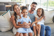 © Alex S/peopleimages.com - Father, mother and children smile, love and relax on the sofa together in the house living room. Portrait of happy family bonding in a lounge with happiness, care and trust in a healthy relationship