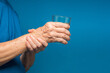© meeboonstudio - Close-up of hands senior woman trying to hold a glass of water