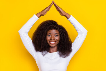 Sticker - Photo of pretty positive girl toothy smile arms make roof gesture above head isolated on yellow color background