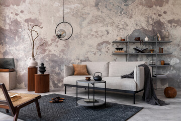 Loft style of modern apartment with grey design sofa, armchairs, ladder, black coffee table, black ladder, pedant lamp, carpet, decoration and elegant accessories . Concrete grunge wall. Template.	