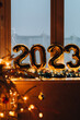 Leinwandbild Motiv 2023 golden foil balloons on blue window sill. Celebrating holidays at home, festive decor concept. Happy New Year 2023. close-up numbers of year 2023 on dark background. Bokeh warm garland light.
