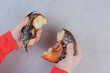 Female hands splitting the donut on stone surface