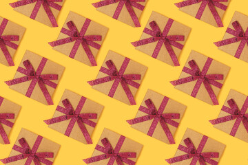 Repetitive pattern made from gift boxes with red ribbons. Creative concept on a yellow background.