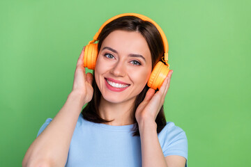 Wall Mural - Photo of adorable cute lady toothy smile hands touch headphones isolated on green color background