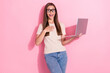 © deagreez - Photo of charming funny excited positive young girl wear glasses surprised winner lottery online bet hold computer isolated on pink color background