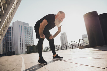 Canvas Print - Photo of tired exhausted sportive pensioner man take break catch heavy breath sunset training urban town outdoors