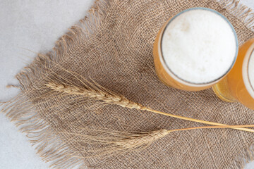 Two glasses of beer on burlap with wheat