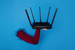 © alesmunt - black wifi router on hand over blue background