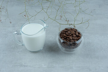 A glass cup of milk with coffee beans on white background