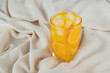 A glass of orange juice with ice cubes on sateen cloth